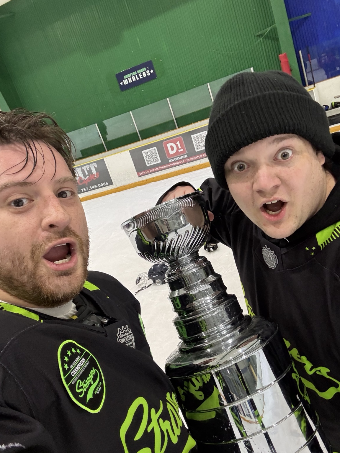 Two Strangers teammates take a selfie with the championship trophy on the ice.