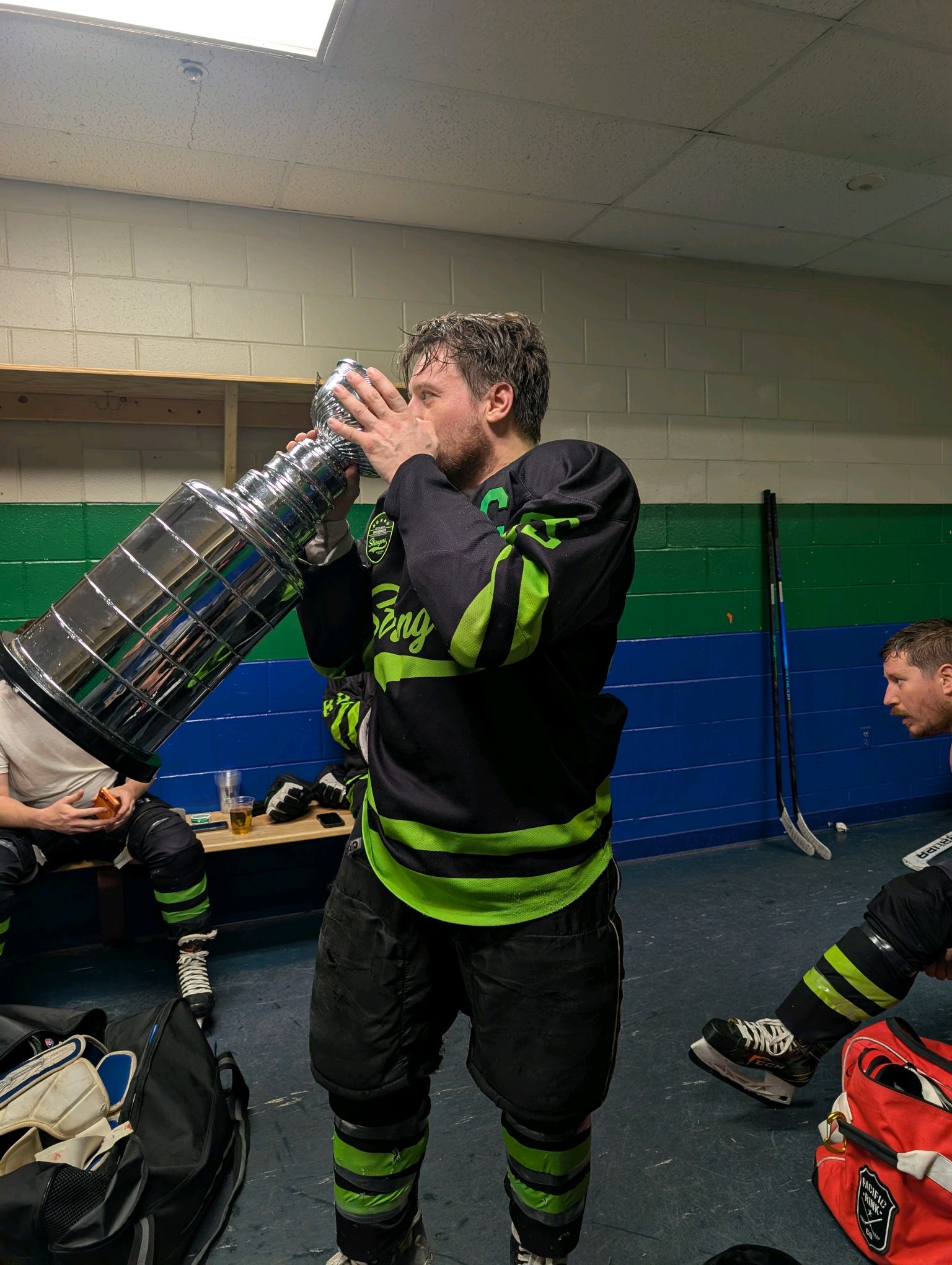 A Strangers player celebrates with the championship trophy in the locker room.